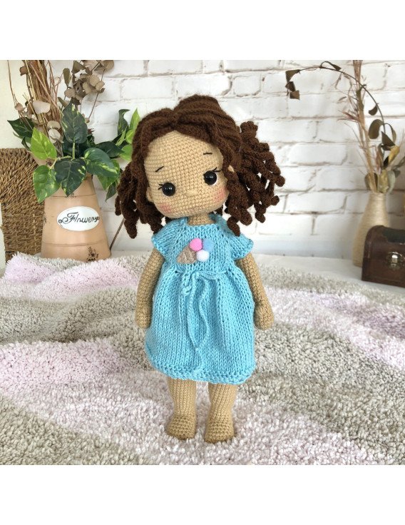 Treffen Sie die geflochtene Häkelpuppe mit braunem Haar und blauem Kleid mit Eiscreme-Aufdruck