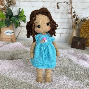Treffen Sie die geflochtene Häkelpuppe mit braunem Haar und blauem Kleid mit Eiscreme-Aufdruck